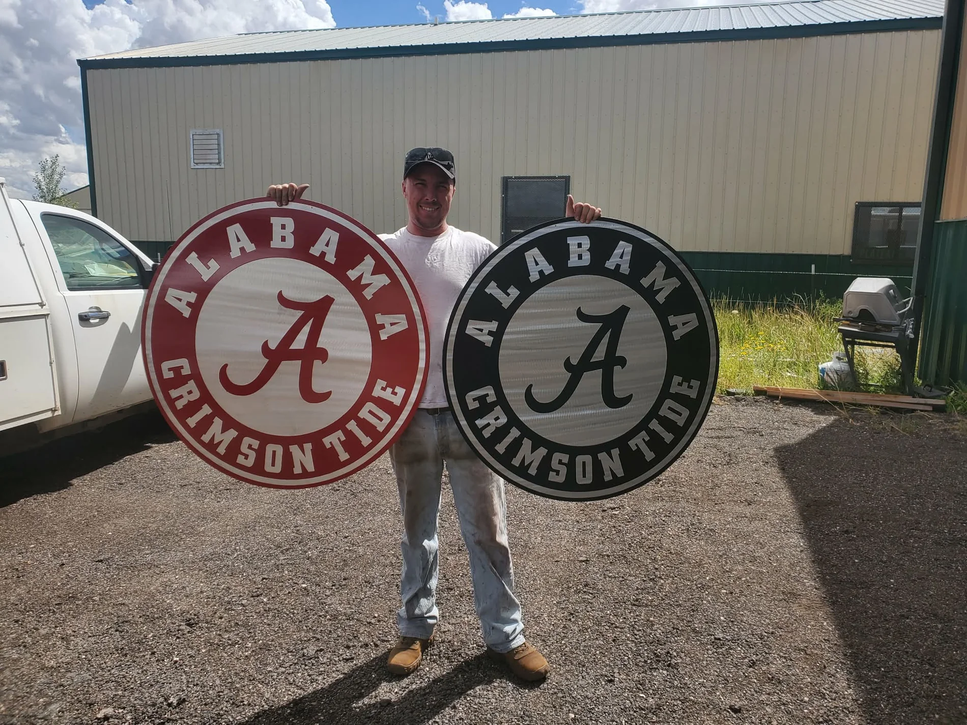 Adam holding two solid-aluminum University of Alabama signs finished in Crimson Red and Hammer Black powder coat